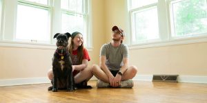 Young couple sitting on the floor of their house with their dog