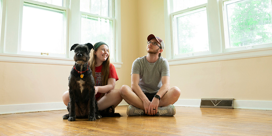 Young couple sitting on the floor of their house with their dog