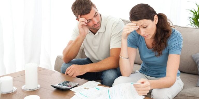 Worried couple doing their accounts in the living room at home